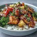 Fluffy white rice topped with glazed chicken and colorful vegetables in a teriyaki sauce.