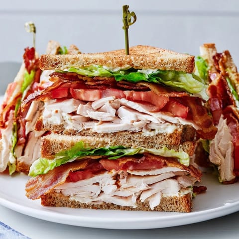 Triple-layered Turkey Club Sandwich, displaying toasted bread, turkey, bacon, and fresh lettuce, perfect for lunch.