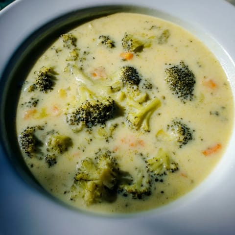 Steaming hot bowl of Broccoli Cheese Soup with melted cheddar, perfect for a cozy dinner.