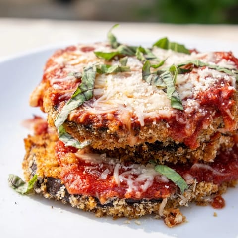 A close-up of a bubbling Eggplant Parmesan, revealing melted mozzarella over tender eggplant.
