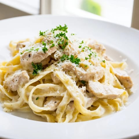 A close-up of steaming fettuccine Alfredo, showcasing the rich, cheesy, and inviting sauce.