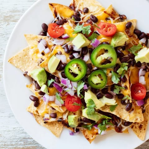 A colorful platter of fully loaded nachos, perfect for your next party or game day snack.