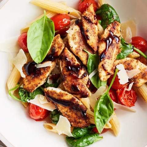 Plated Balsamic Glazed Chicken Pasta with seared chicken and vibrant cherry tomatoes on the side.