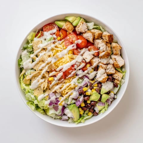 Close-up of Chicken Taco Chopped Salad topped with crushed tortilla chips, cheese, and diced avocado.  