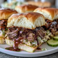 Smoky BBQ brisket sliders with tangy sauce and crisp slaw on soft buns, perfect for parties and celebrations.  